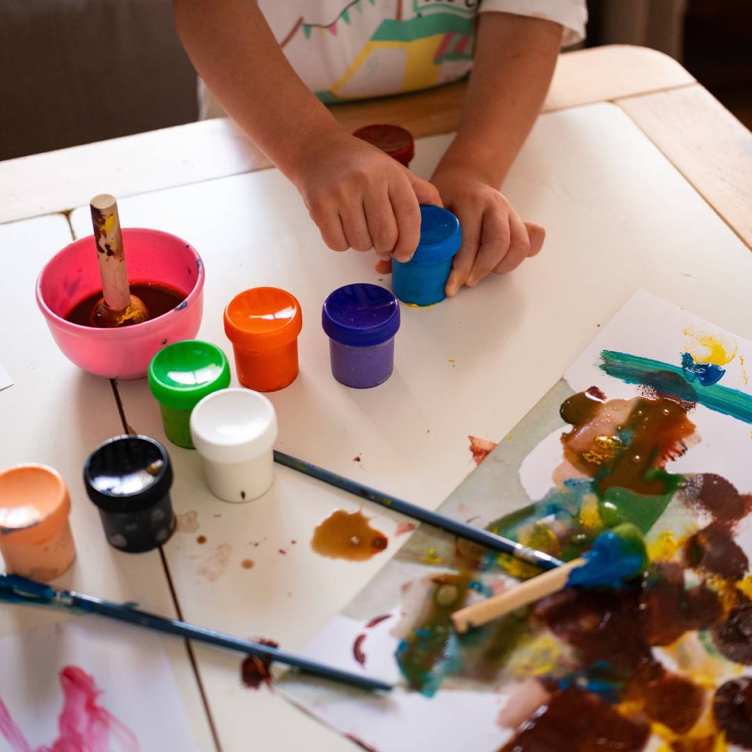 Photo of a child opening a small pot of paint during arts & crafts time