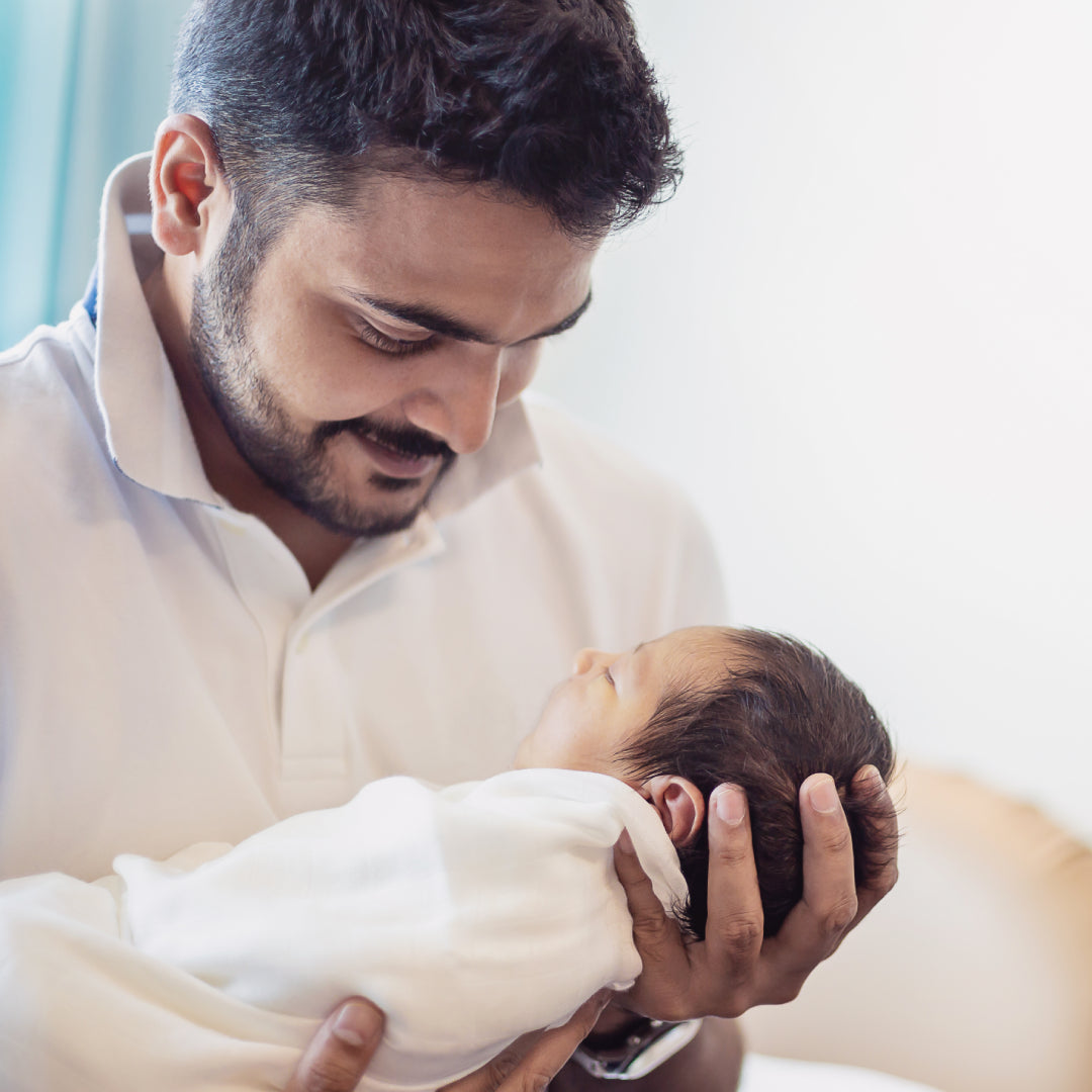 Dad smiling & cradling his newborn baby