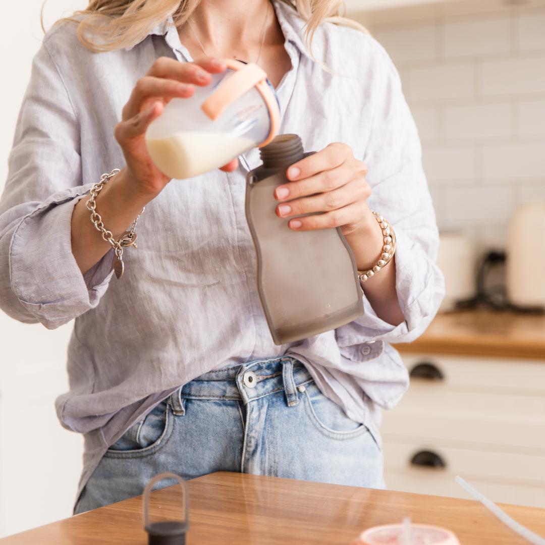 Mum pouring expressed breastmilk from container into Haakaa Milk Storage Bag