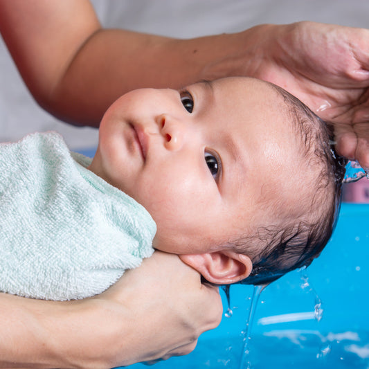 Swaddled newborn baby having their hair washed